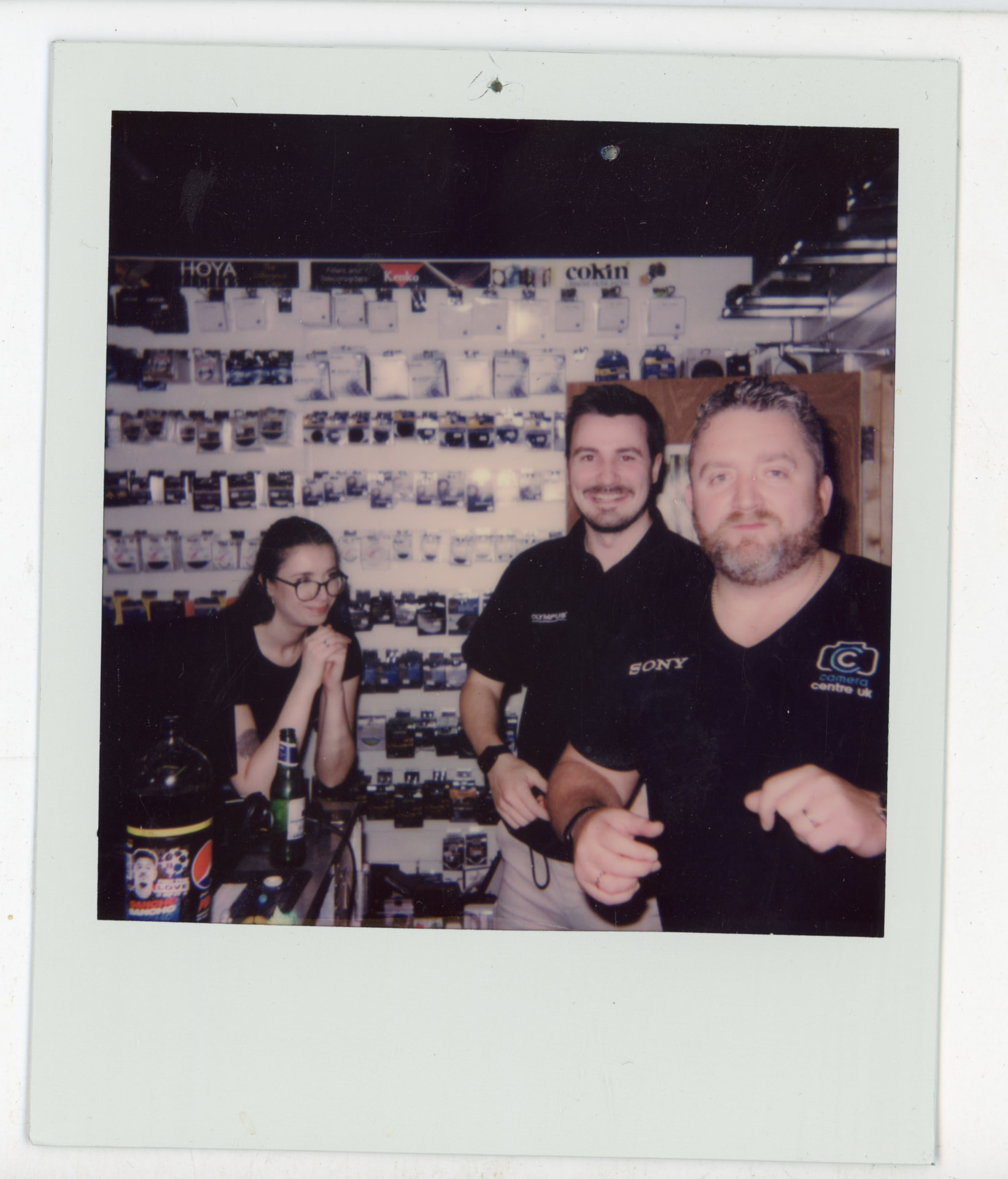 Polaroid photo of three Camera Centre UK staff by the filter wall